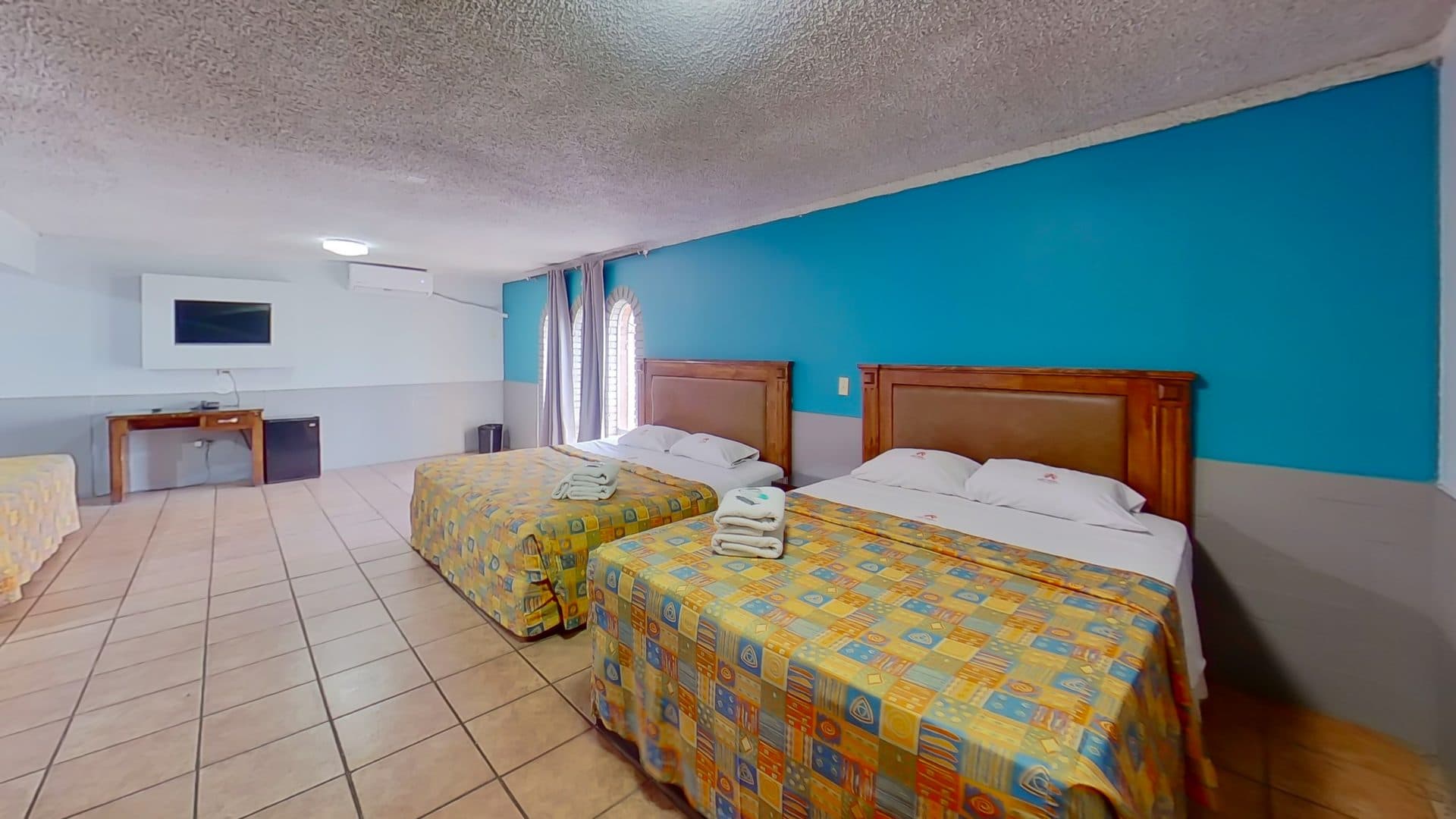 Dos camas matrimoniales de la habitación doble con muro turquesa